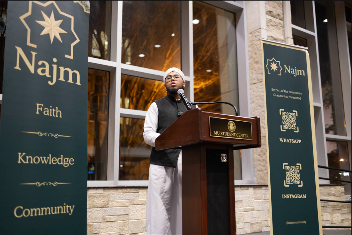 Ustadh Yusuf Abdullah Islam speaking at a Najm event at the MU Student Center, framed by Najm banners